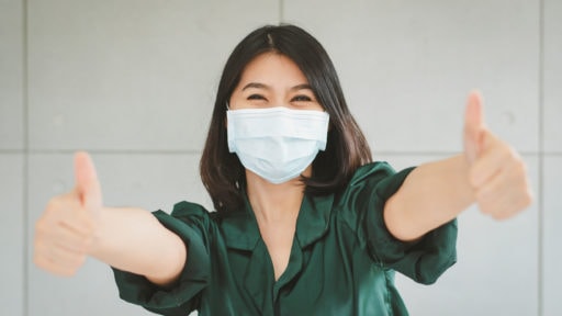 Young woman wearing a mask giving thumbs up
