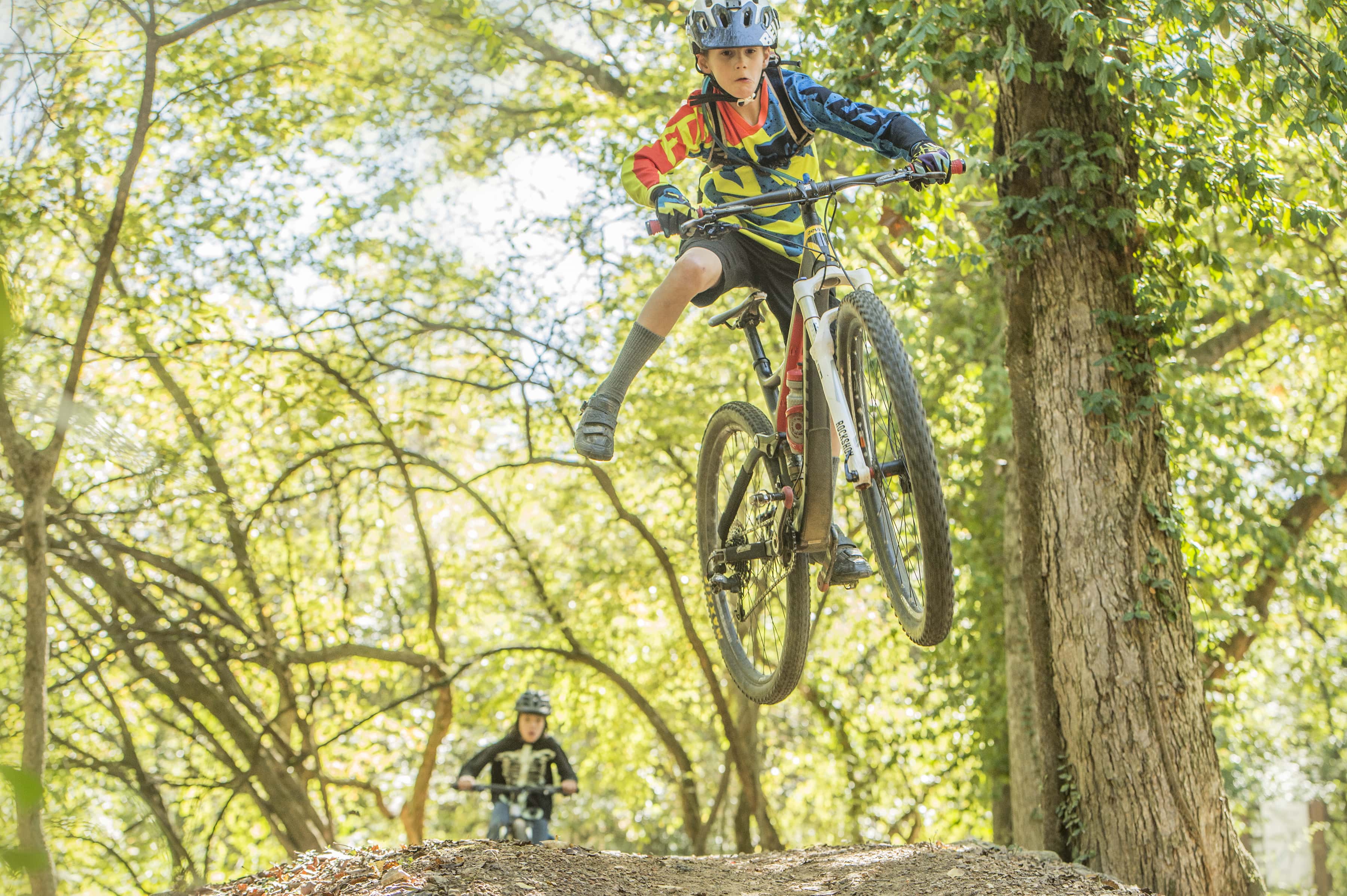 Kids riding on a bike trail. One kid is airborne.