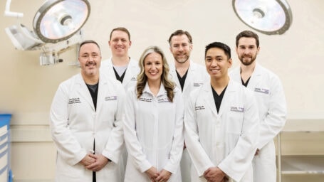 Group Photo of EM Residency faculty standing in a procedure room.