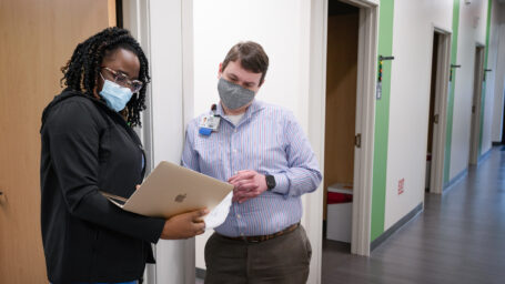 A resident and faculty member converse in a hallway