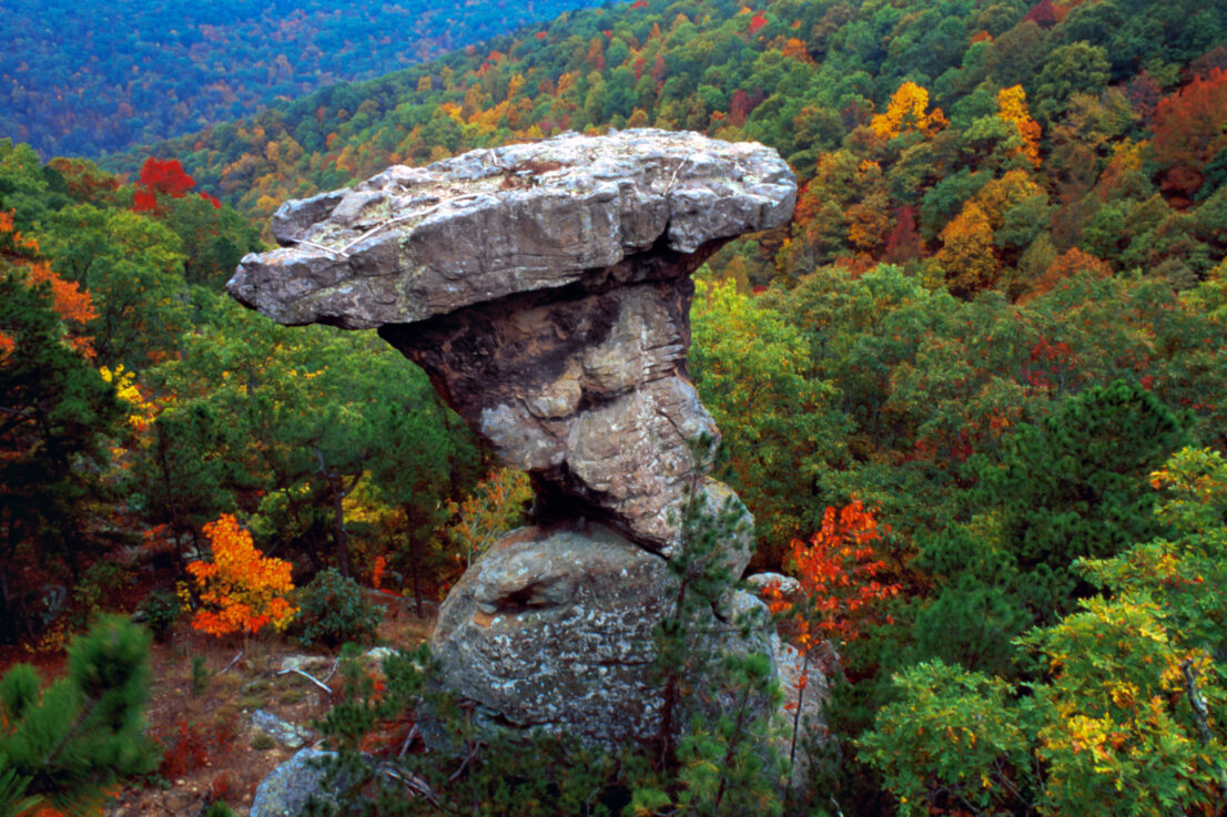 rock formation with trees in the background. Trees are in autumn colors.