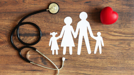 White paper cut of family, stethoscope and heart on wooden background top view. Health medical insurance concept.